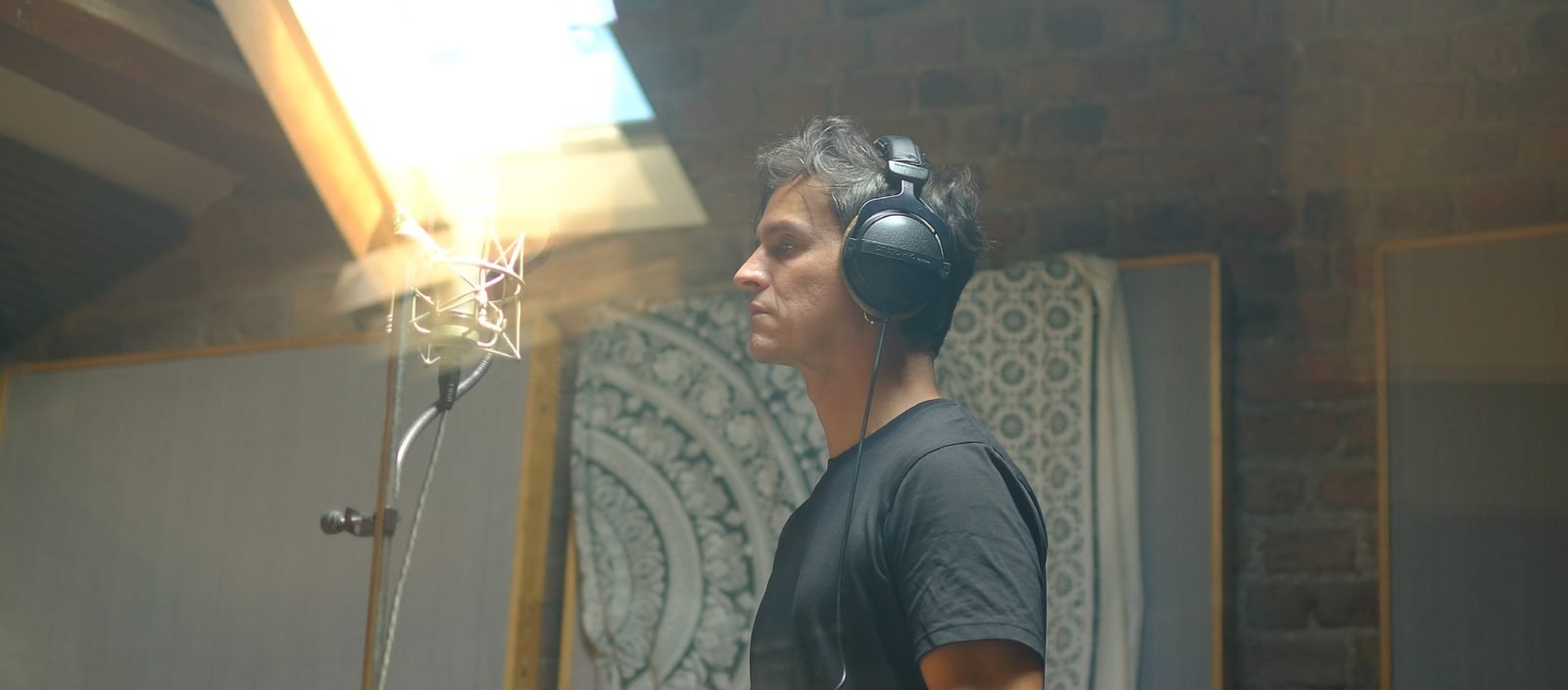 Anderson Tombini em estúdio caseiro, de perfil, usando fones de ouvido / Anderson Tombini in his home studio, in profile, wearing headphones
